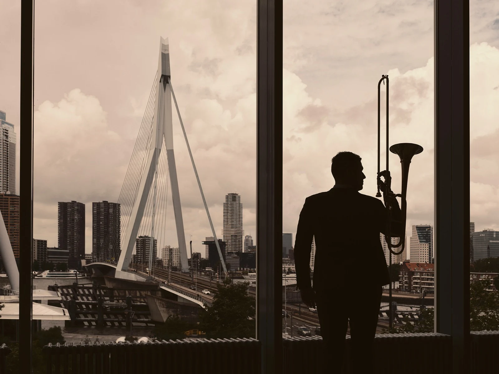 Alejandro and his trombone silhouetted against the Rotterdam skyline
